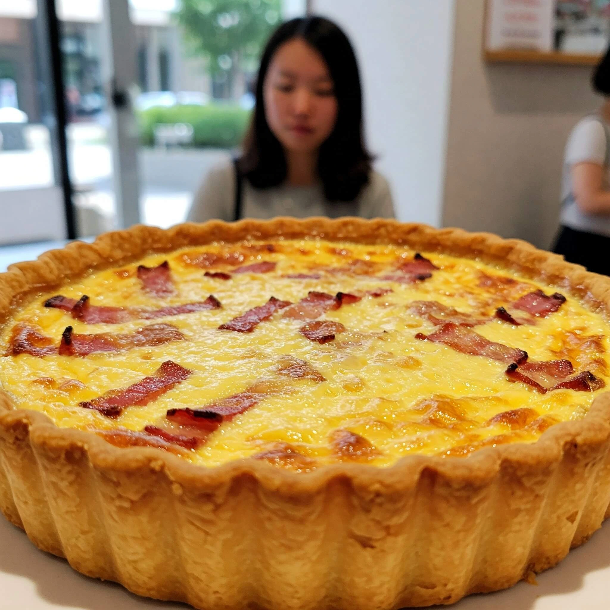 Quiche Lorraine maison avec une pâte croustillante et une garniture fondante aux lardons, servie sur une assiette avec une salade verte.